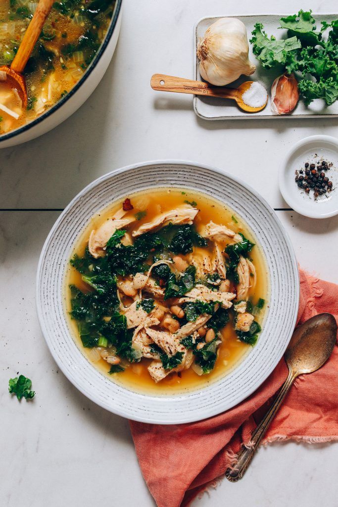 Sopa de pollo en una olla con frijoles blancos y col rizada