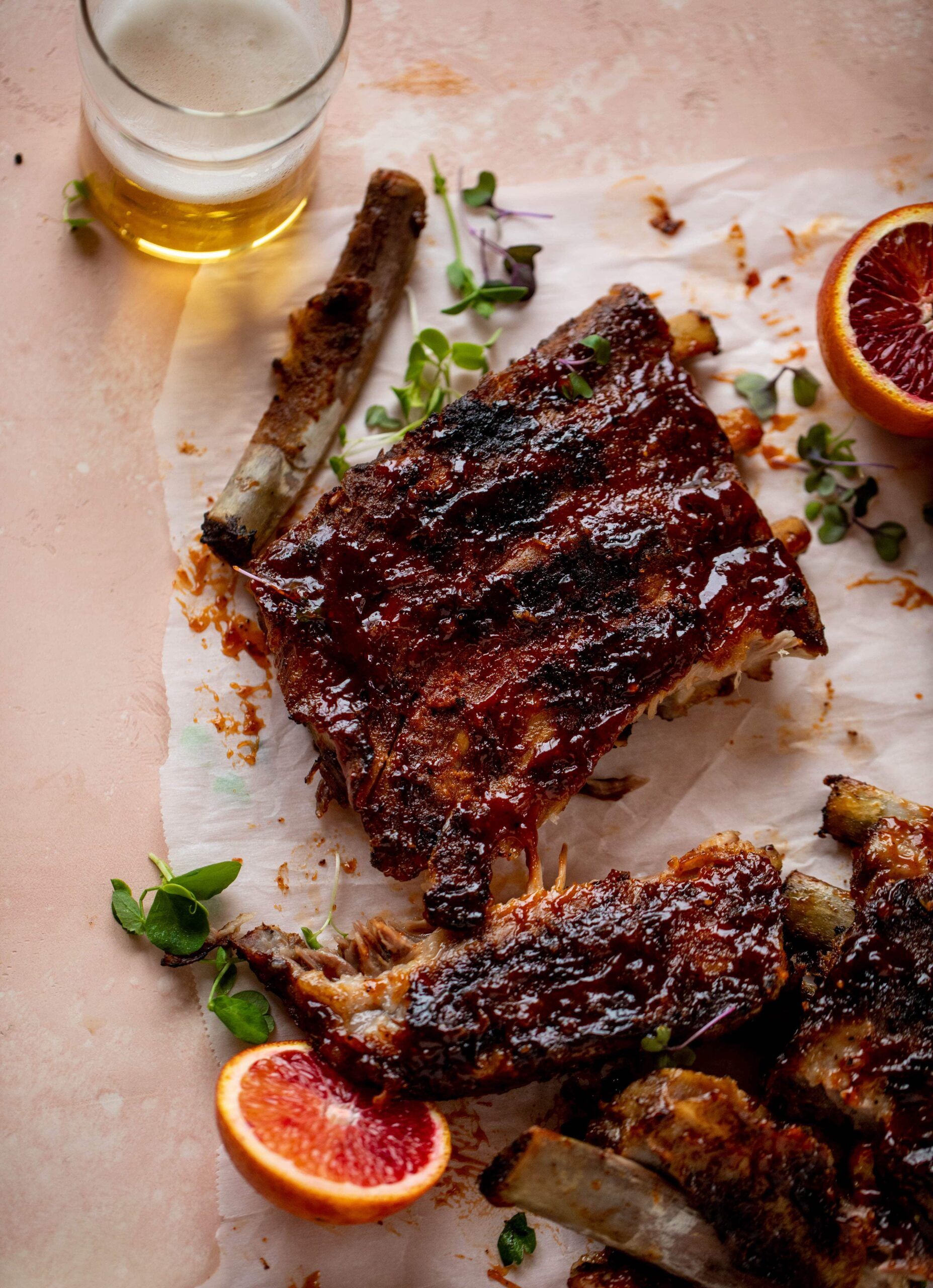 Costillas de barbacoa de naranja sanguina ahumada con verdes de mantequilla de aguacate.